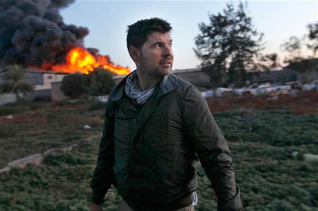 Getty photographer Chris Hondros in front of a burning building while on assignment on Monday, April 18, 2011, in Misrata, Libya